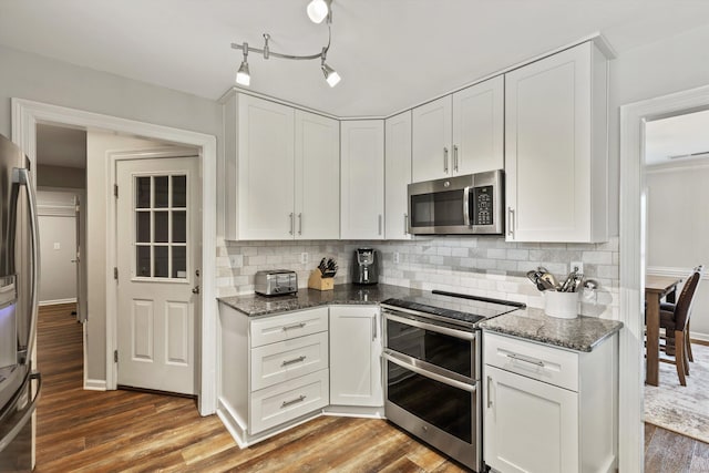 kitchen with appliances with stainless steel finishes, wood finished floors, white cabinetry, and decorative backsplash