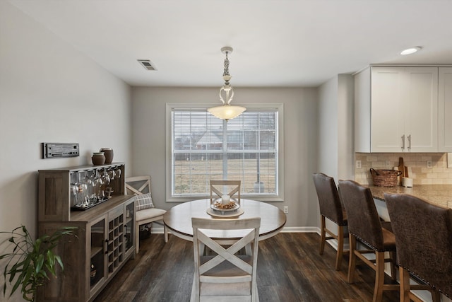 dining space featuring dark wood-type flooring, visible vents, and baseboards