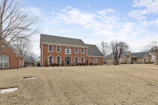 colonial home with cooling unit and brick siding