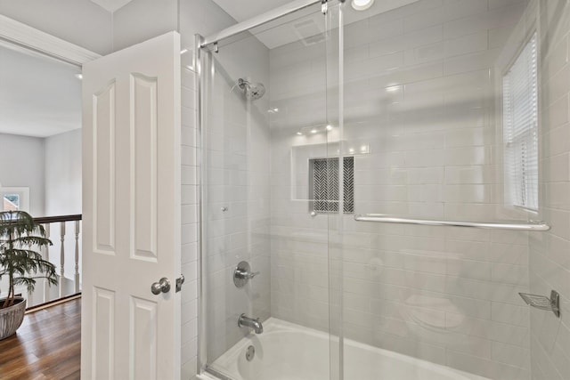 full bath with bath / shower combo with glass door and wood finished floors