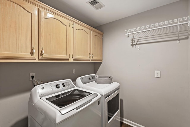 washroom with washer and dryer, cabinet space, visible vents, and baseboards