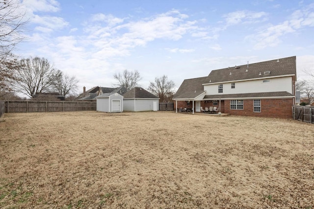 view of yard featuring a patio area, a fenced backyard, an outdoor structure, and a storage unit