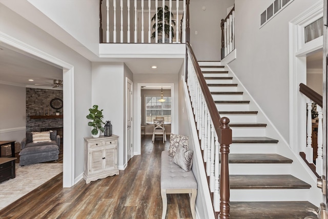 foyer with a towering ceiling, stairway, visible vents, and wood finished floors