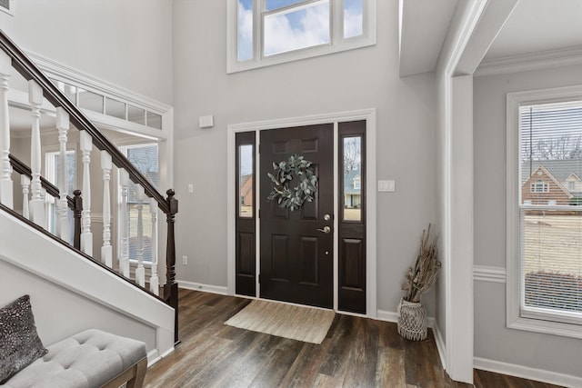 foyer entrance with dark wood-style flooring, crown molding, stairway, and baseboards