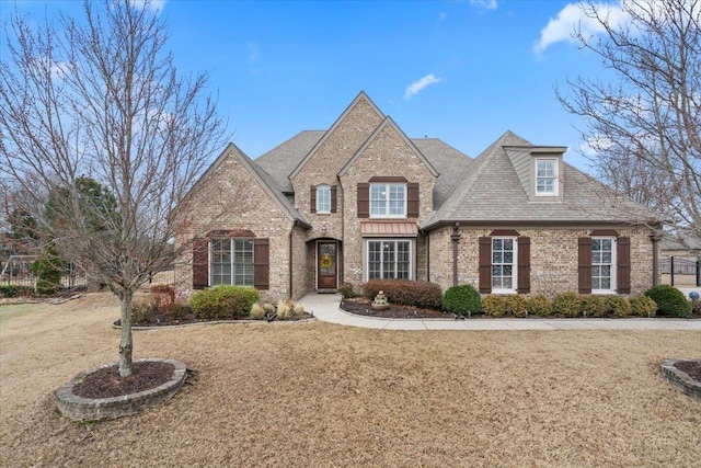 french country home featuring a front yard and brick siding