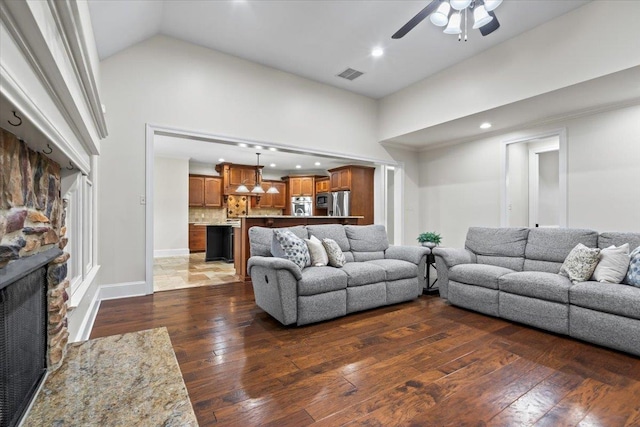 living room featuring high vaulted ceiling, visible vents, a stone fireplace, and hardwood / wood-style flooring