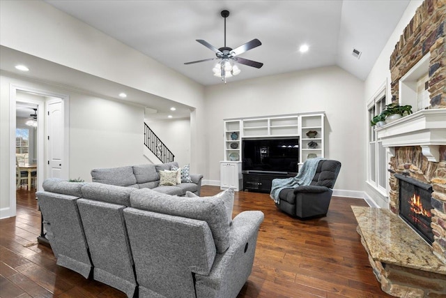 living room with dark wood-type flooring, a fireplace, ceiling fan, and stairs