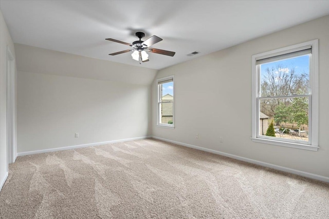 empty room with ceiling fan, carpet floors, visible vents, baseboards, and vaulted ceiling