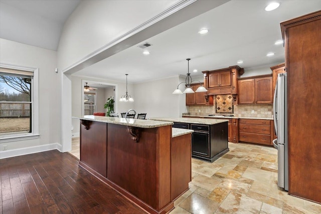 kitchen with a center island, tasteful backsplash, stainless steel appliances, a kitchen breakfast bar, and baseboards