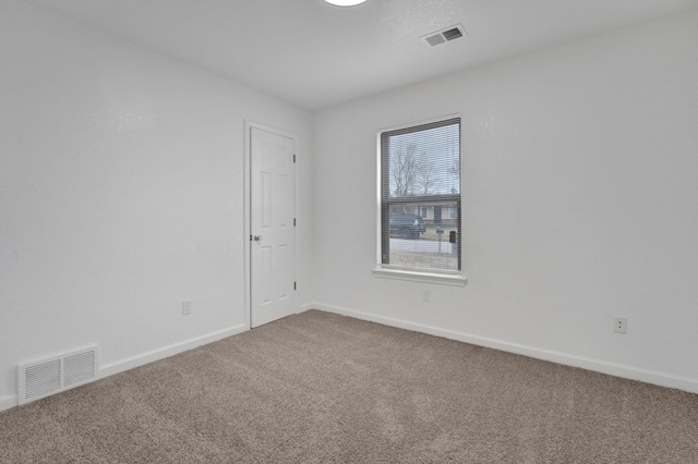 empty room with baseboards, visible vents, and carpet flooring