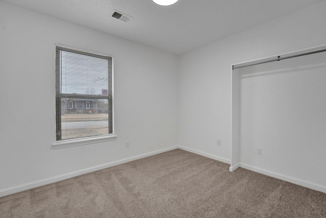 spare room featuring light carpet, visible vents, and baseboards