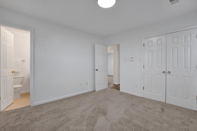 unfurnished bedroom with carpet floors, a closet, baseboards, and connected bathroom