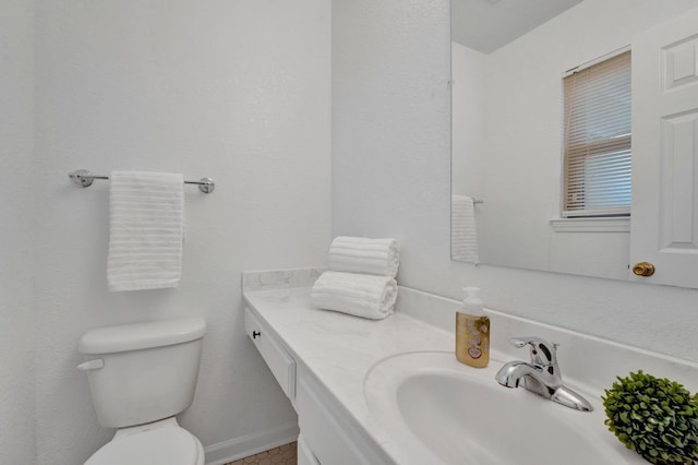 bathroom featuring vanity, toilet, and baseboards