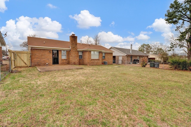 rear view of property with a gate, a fenced backyard, a lawn, and brick siding