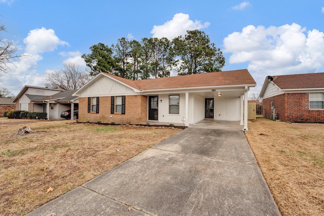 ranch-style home with driveway, brick siding, an attached carport, and a front yard