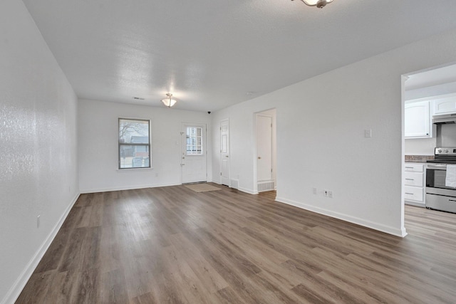 unfurnished living room featuring baseboards and wood finished floors