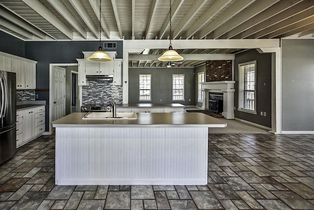 kitchen with backsplash, a sink, freestanding refrigerator, and white cabinetry