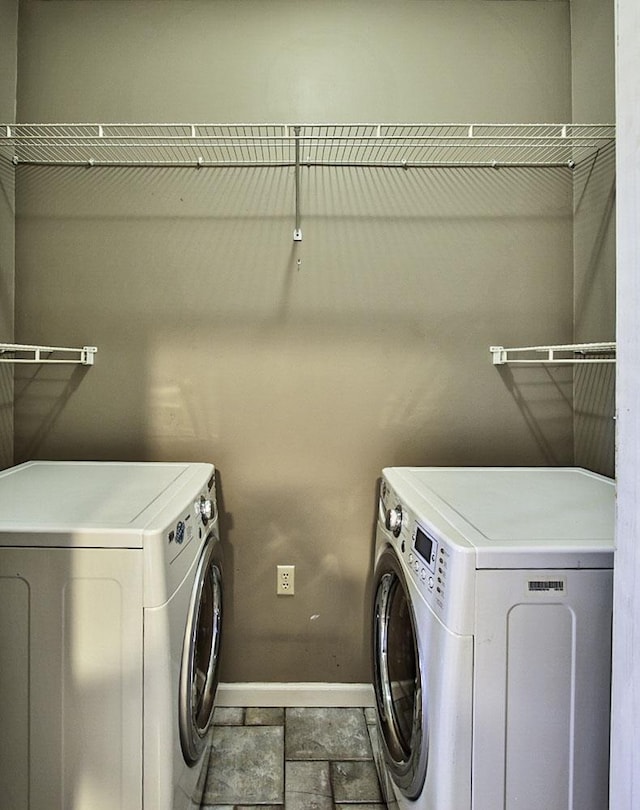 clothes washing area with laundry area, baseboards, and washing machine and clothes dryer