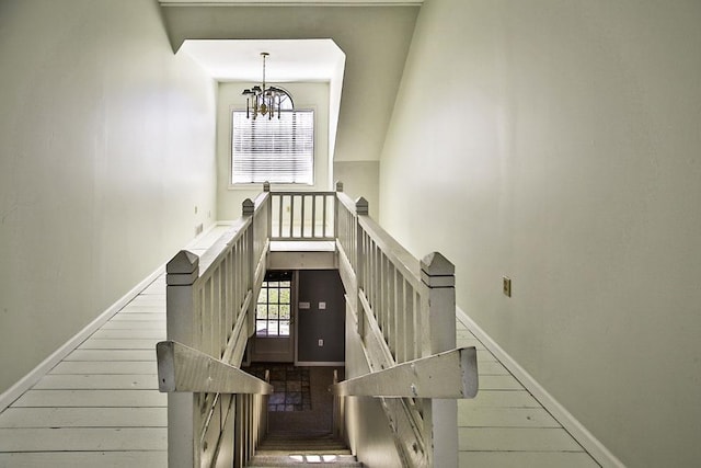 staircase featuring baseboards, a healthy amount of sunlight, and an inviting chandelier