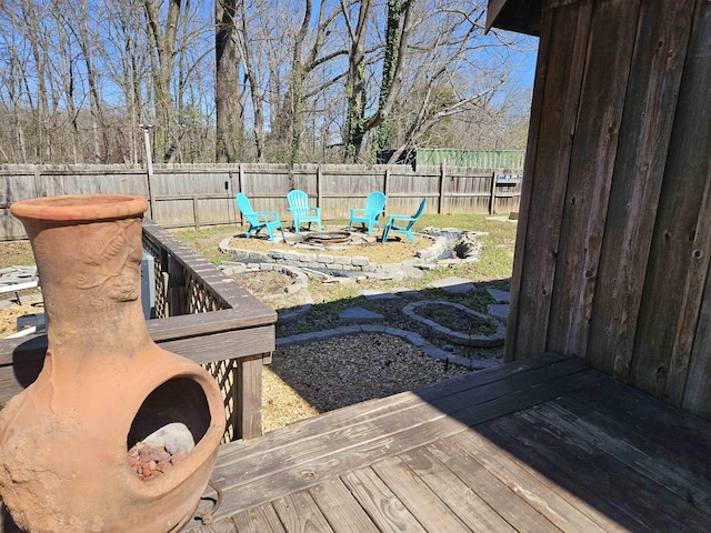 wooden deck with an outdoor fire pit and a fenced backyard