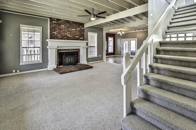 staircase with baseboards, beamed ceiling, carpet floors, a fireplace, and ceiling fan with notable chandelier