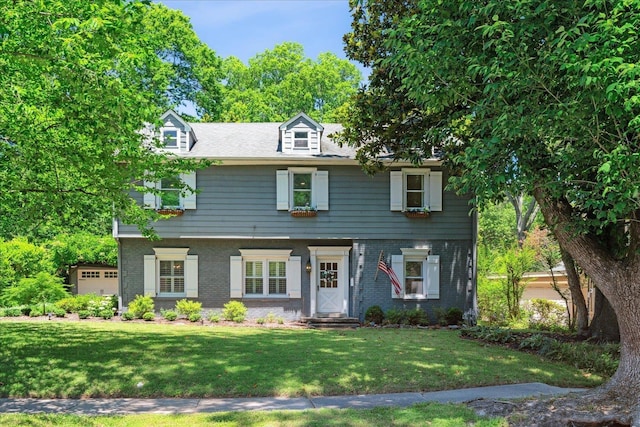 colonial inspired home featuring a front yard and brick siding