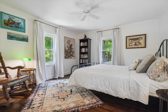 bedroom featuring a ceiling fan, crown molding, baseboards, and wood finished floors