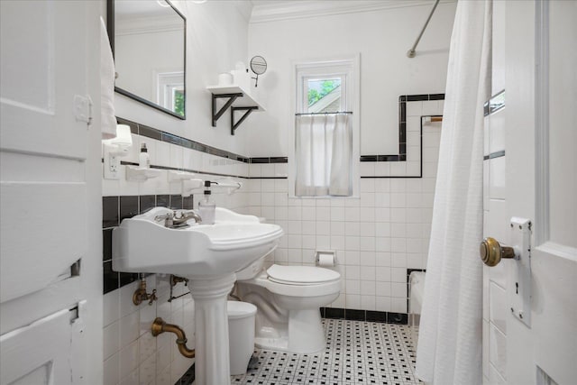 full bathroom with wainscoting, toilet, a shower with shower curtain, crown molding, and tile walls