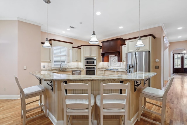 kitchen featuring arched walkways, a sink, visible vents, light wood-style floors, and appliances with stainless steel finishes