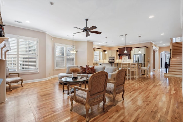 dining space featuring arched walkways, light wood-style flooring, visible vents, stairs, and ornamental molding