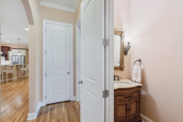 interior space featuring baseboards, wood finished floors, vanity, and crown molding