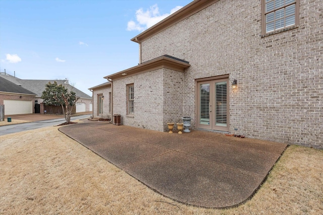 view of side of home featuring a patio area, french doors, and brick siding