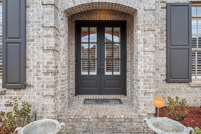 view of exterior entry with french doors and brick siding