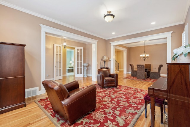 living area with a chandelier, french doors, wood finished floors, and visible vents