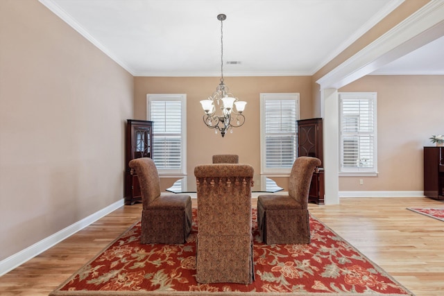 dining space featuring crown molding, light wood-type flooring, baseboards, and an inviting chandelier