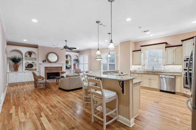 kitchen featuring stainless steel appliances, a breakfast bar, a fireplace, open floor plan, and light wood finished floors