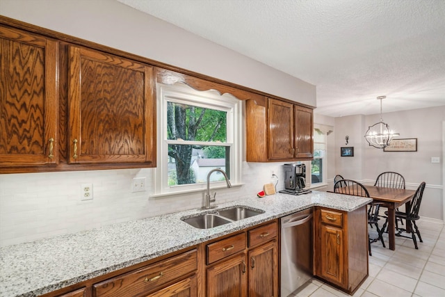 kitchen with stainless steel dishwasher, backsplash, brown cabinetry, and a sink