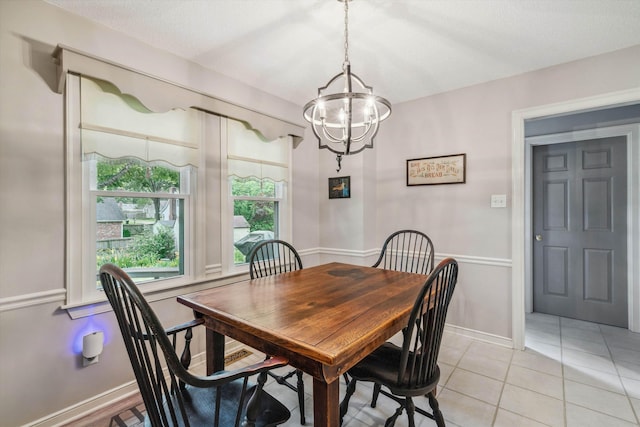 dining area featuring a chandelier, light tile patterned flooring, and baseboards