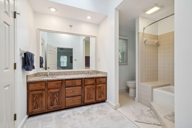 bathroom featuring toilet, double vanity, a washtub, and a sink