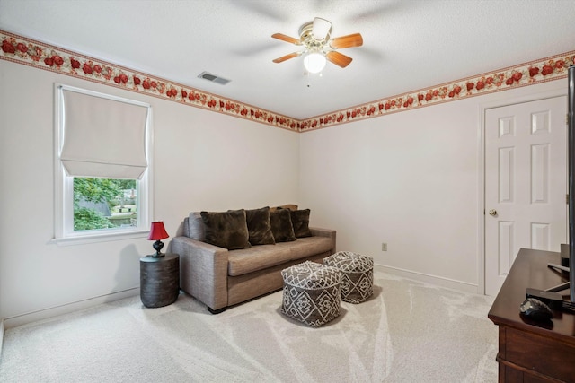 living area with visible vents, baseboards, a ceiling fan, carpet, and a textured ceiling