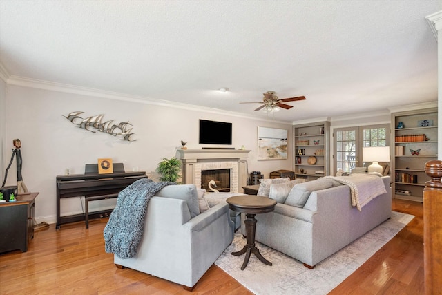 living room featuring ornamental molding, a brick fireplace, light wood finished floors, and a ceiling fan