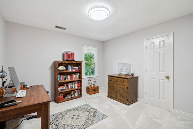 office area with baseboards, visible vents, a textured ceiling, and light colored carpet