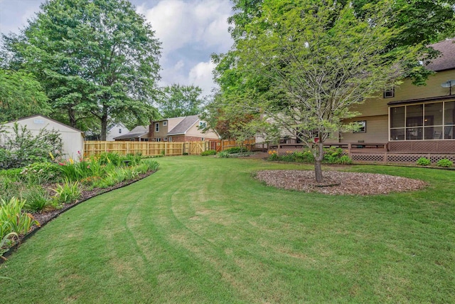 view of yard with a sunroom, fence, and an outdoor structure