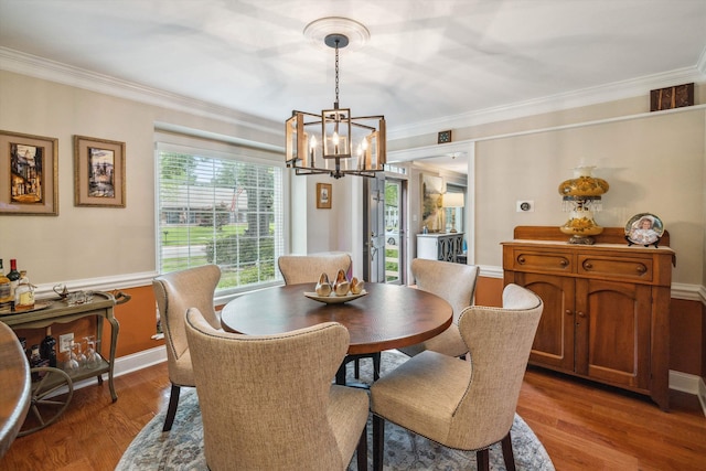 dining room featuring a notable chandelier, baseboards, wood finished floors, and crown molding