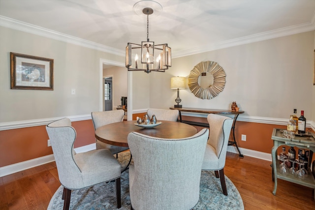 dining room featuring a notable chandelier, crown molding, baseboards, and wood finished floors