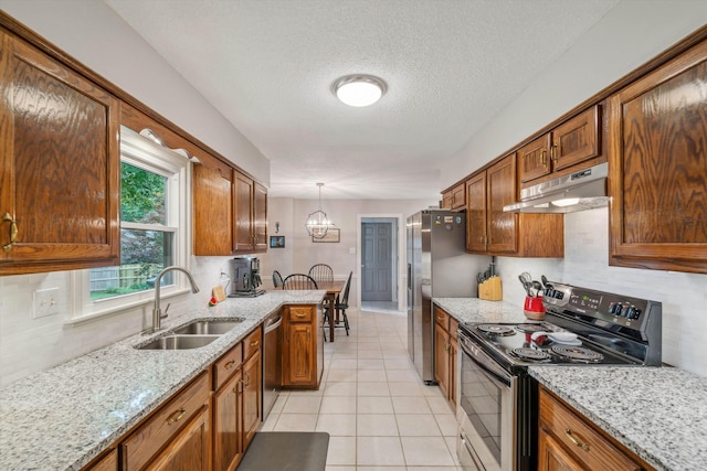 kitchen featuring brown cabinets, under cabinet range hood, stainless steel appliances, and a sink