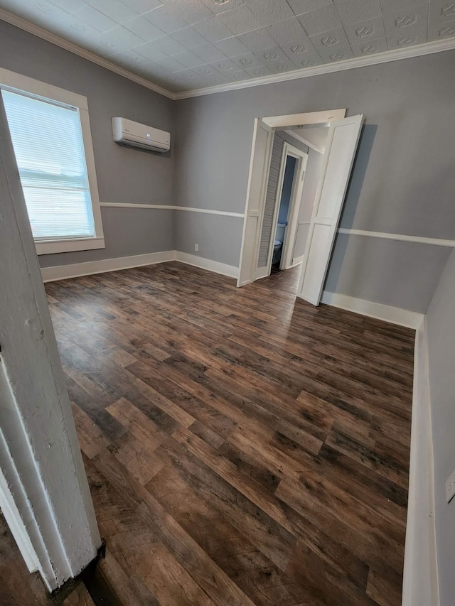 unfurnished room featuring baseboards, dark wood-type flooring, a wall unit AC, and crown molding