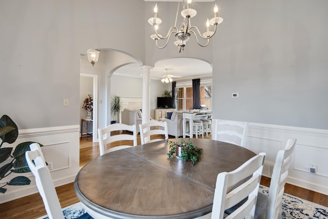 dining space featuring a wainscoted wall, arched walkways, and wood finished floors