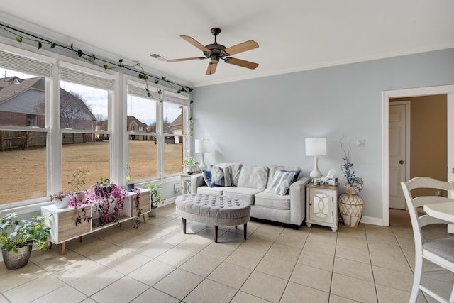 living area with light tile patterned floors, visible vents, ornamental molding, ceiling fan, and baseboards