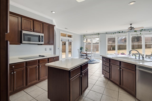 kitchen featuring light tile patterned floors, appliances with stainless steel finishes, light countertops, crown molding, and a sink